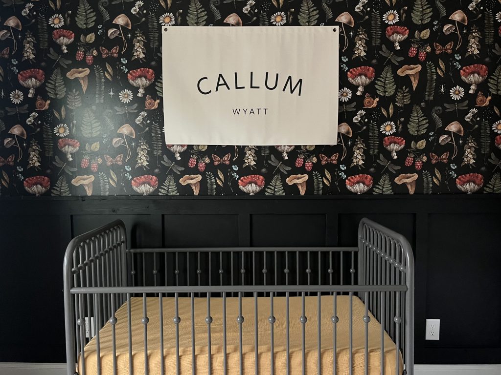 forest and mushroom themed nursery for baby with crib and decorative wallpaper